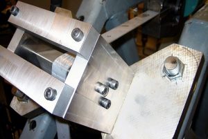 A sheet-steel sample undergoes mechanical testing in a Bending Under Tension test apparatus. This test combines analysis of friction, tooling radius, and material properties to provide an accurate determination of formability. Colorado School of Mines. 
