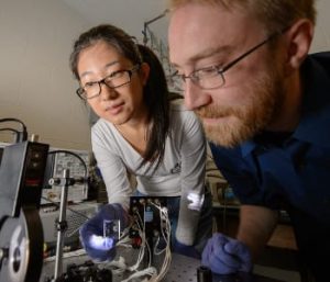 Yimu Zhao, a doctoral student in chemical engineering and materials science, and Richard Lunt, assistant professor of chemical engineering and materials science, run a test in Lunt’s lab. Lunt and his team have developed a new material that can be placed over windows and create solar energy. Photo by G.L. Kohuth. 