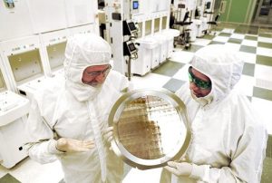 SUNY College of Nanoscale Science and Engineering's Michael Liehr, left, and IBM's Bala Haranand look at wafer comprised of 7nm chips on Thursday, July 2, 2015, in a NFX clean room Albany.   Several 7nm chips at SUNY Poly CNSE on Thursday in Albany.  (Darryl Bautista/Feature Photo Service for IBM)