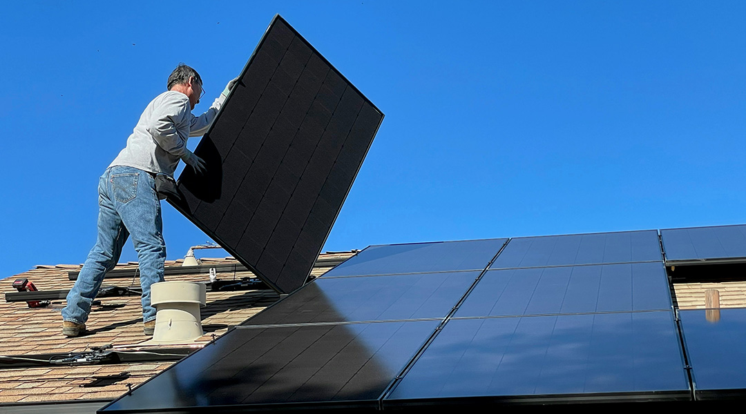 A worker installing solar panels on a roof.