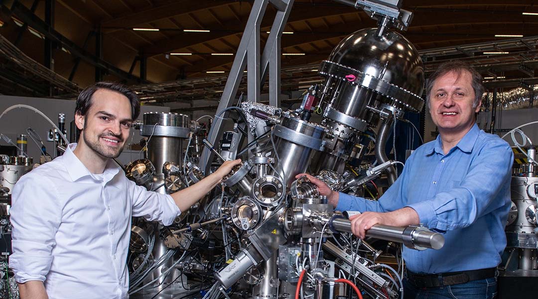 Two researchers developing stable qubits stand in front of experimental machinery