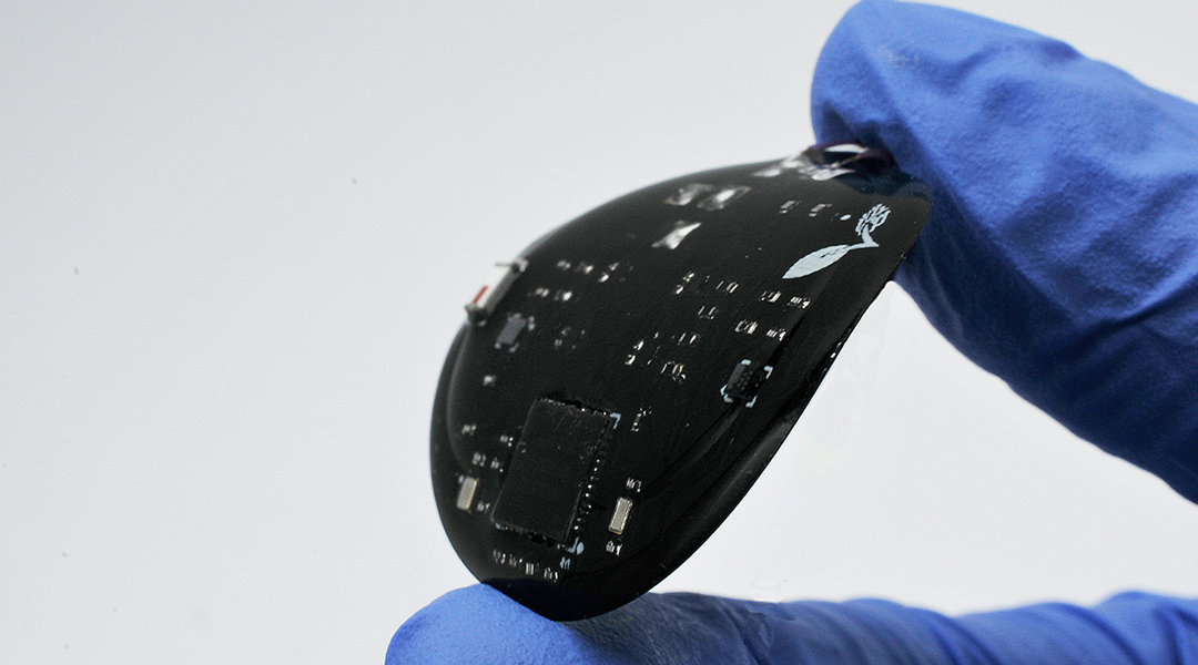 A black sensor held between gloved fingers.