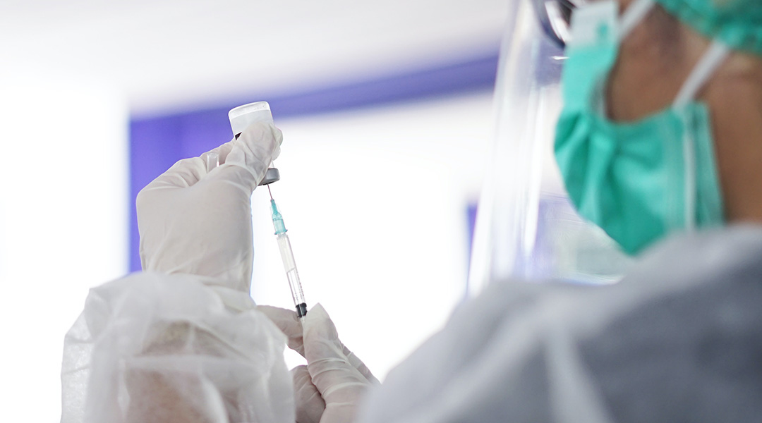 Person loading a syringe with liquid.