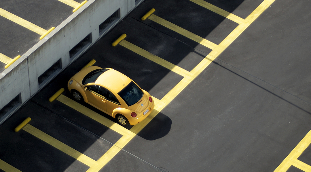 A lone yellow car in a parking lot.