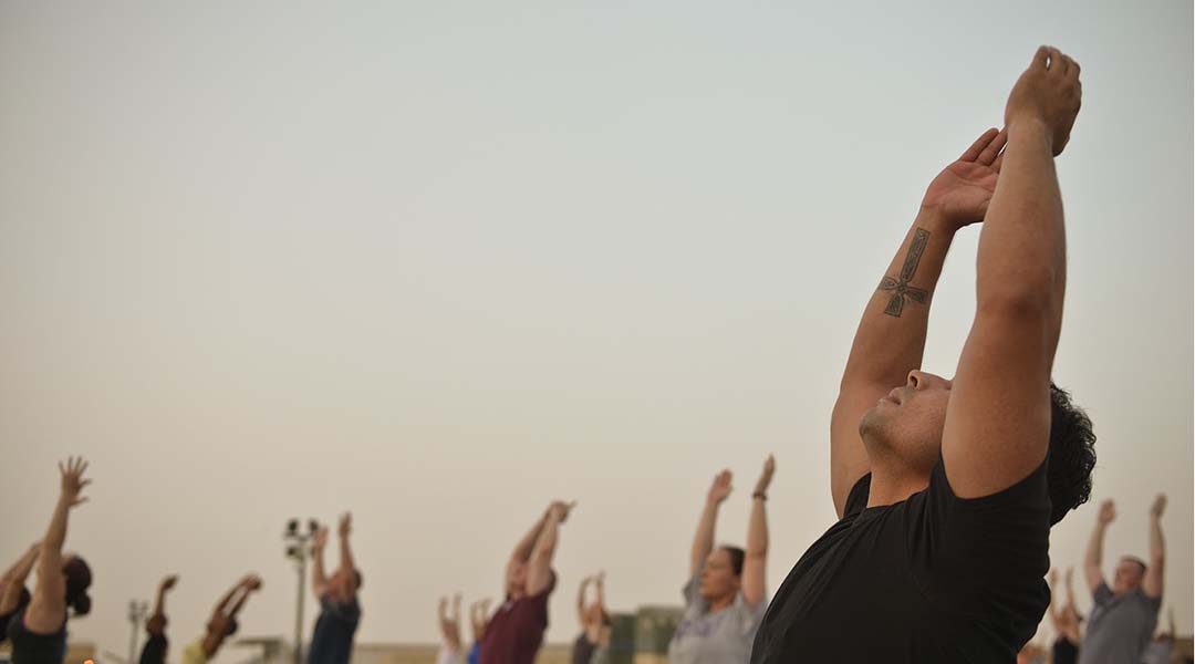 People practicing yoga at sunset.