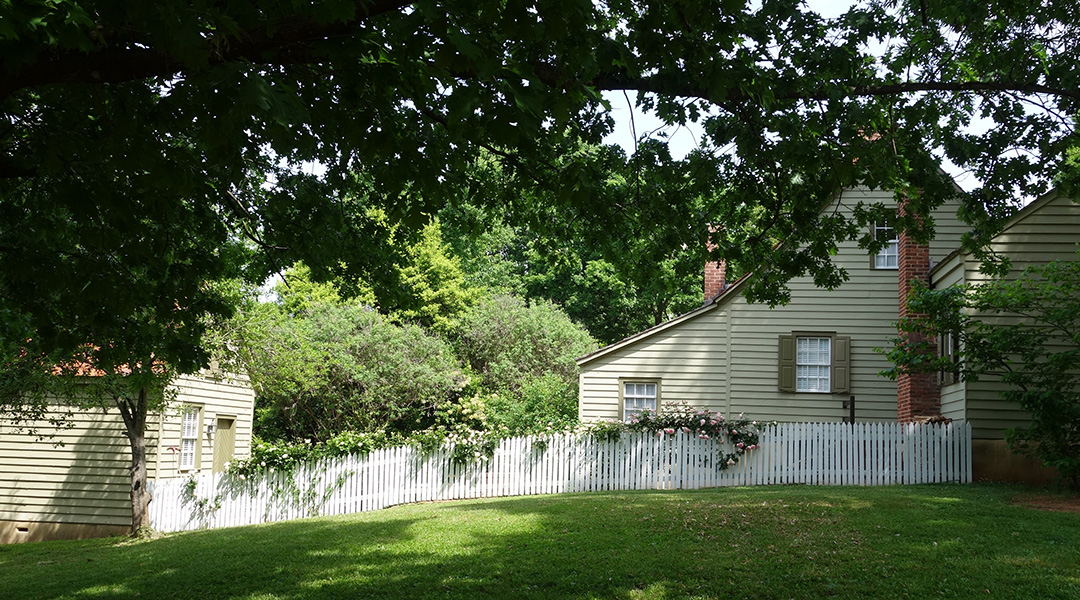 A backyard with a beige house.
