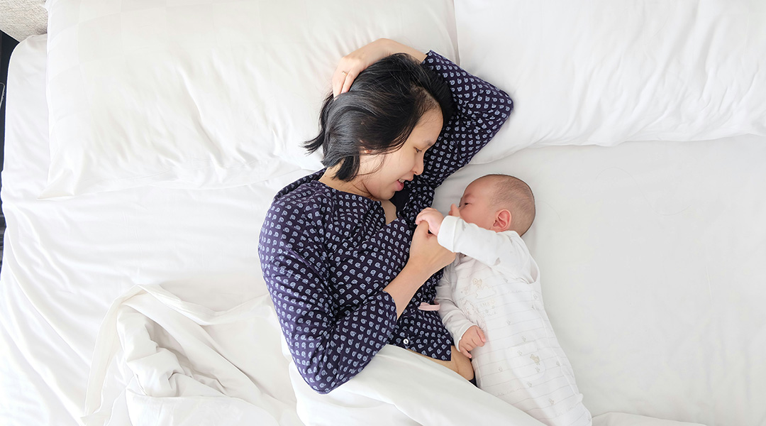 A mother and baby in a bed.