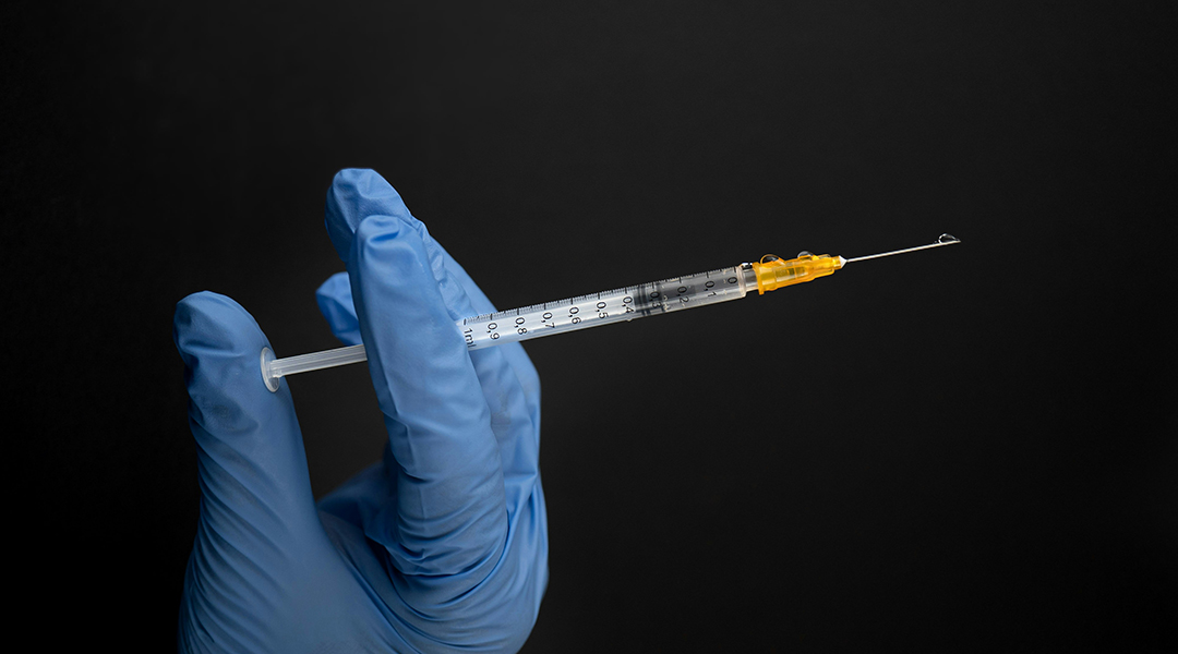 A gloved hand holding a syringe.