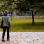 An elderly woman walking through a park.