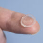 A self-lubricating contact lens held on a fingertip.