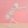 a skeleton stretching against a pink background